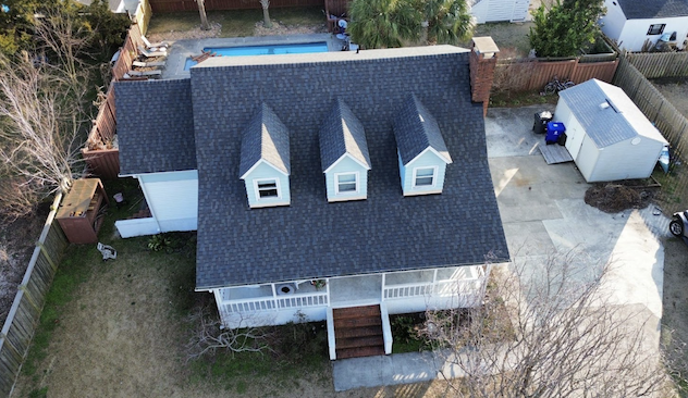 Aerial view of a blue two-story house with grey shingles.