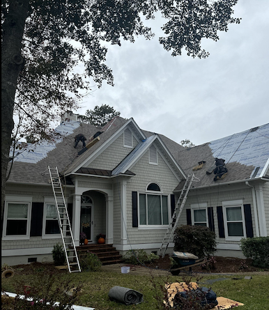 Two roofers installing shingles on house.