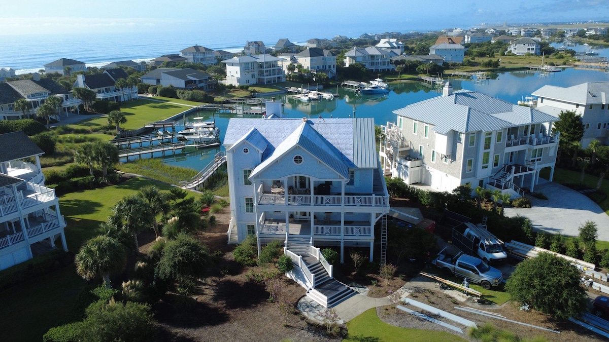 An aerial view shows a coastal neighborhood with large, multi-story houses.