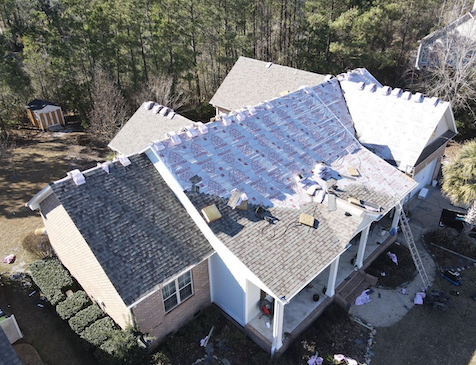 Aerial view of multi-story peach house with tan roof.