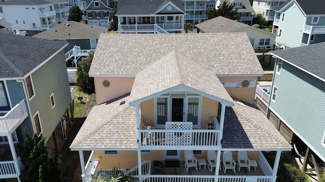 Aerial view of multi-story peach house with tan roof.