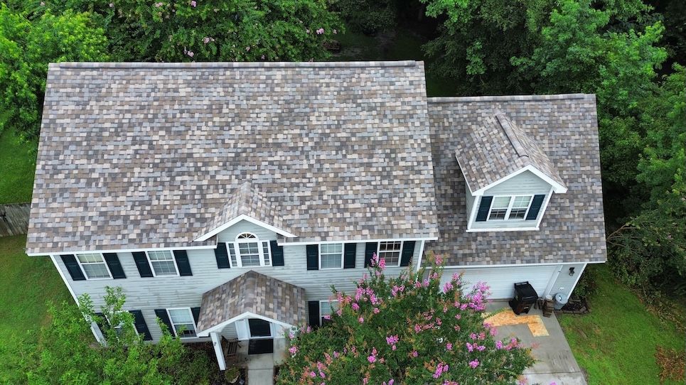 Aerial view of a two-story grey home with architectural shingles.